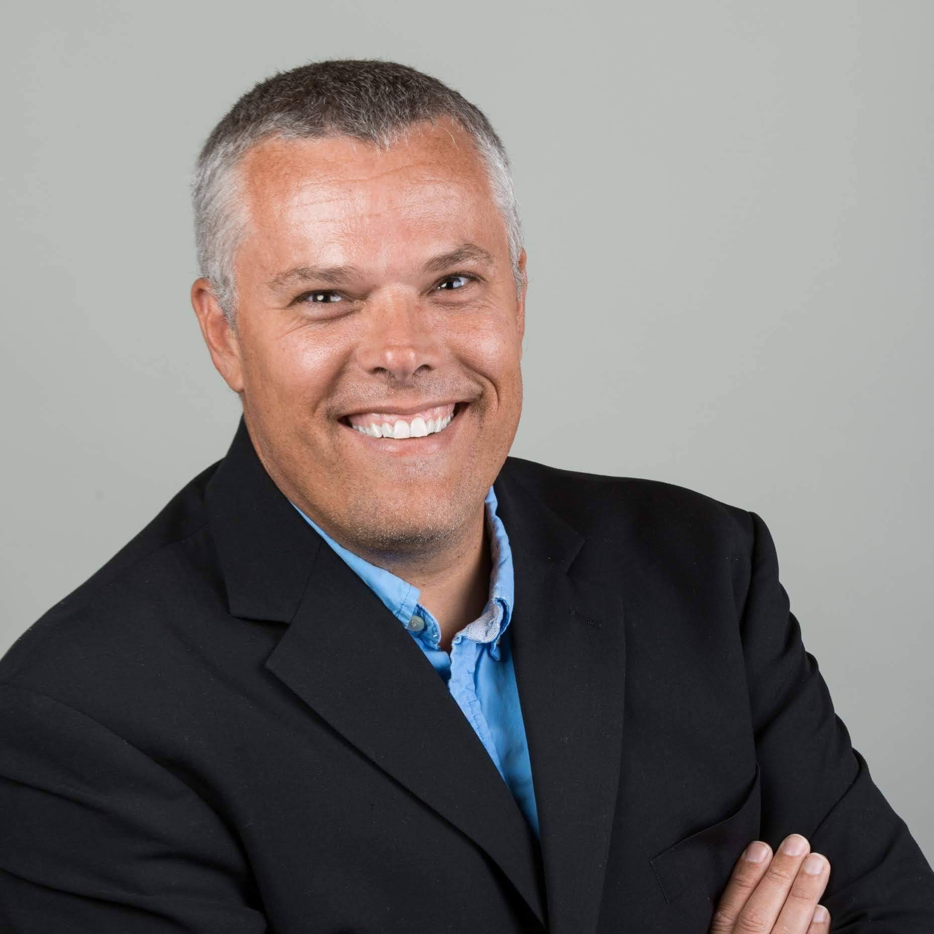 Adam Heunis in a suit, smiling